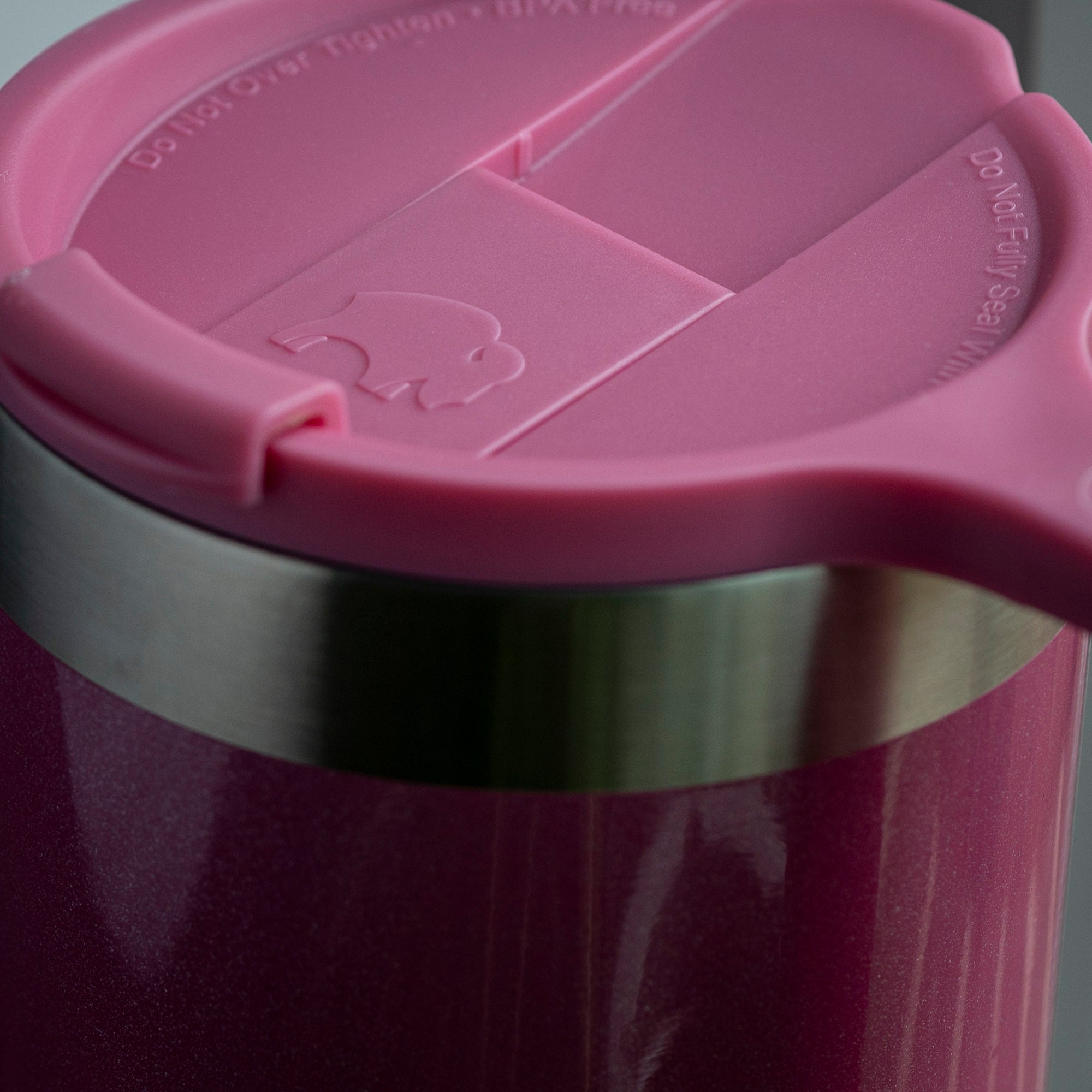 Close-up of a burgundy tumbler with stainless steel band and pink plastic lid from unknown brand.