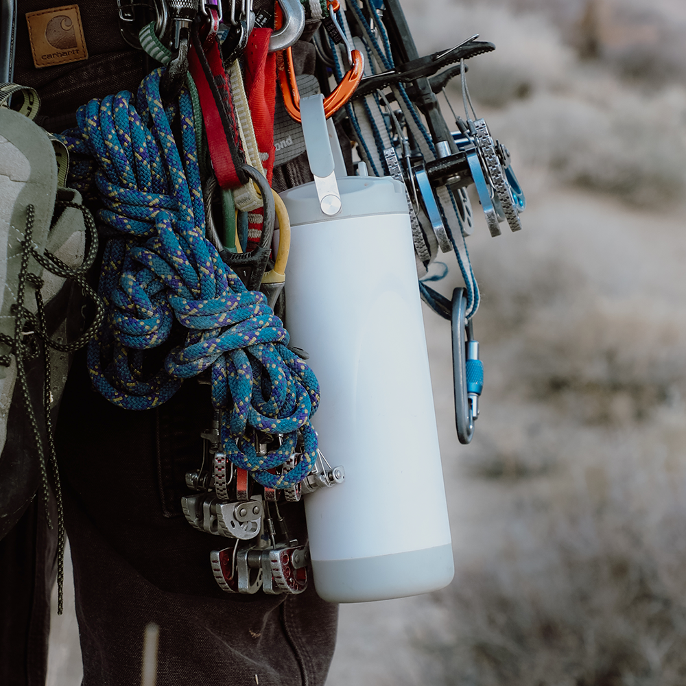 White water bottle by ROVA with a gray base and top handle, hanging with climbing gear.
